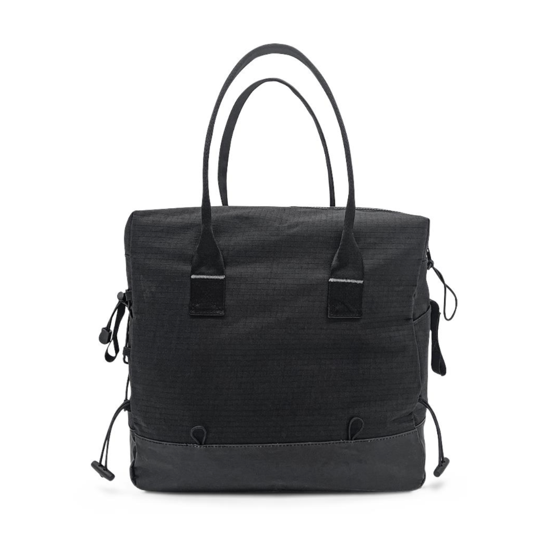The ByAcre Accessories for Overland Carbon Fiber Rollators include a black tote bag with two short handles, a textured surface, adjustable side cords, and subtle stitching. Its minimalist design blends style and functionality, making it perfect for everyday use.